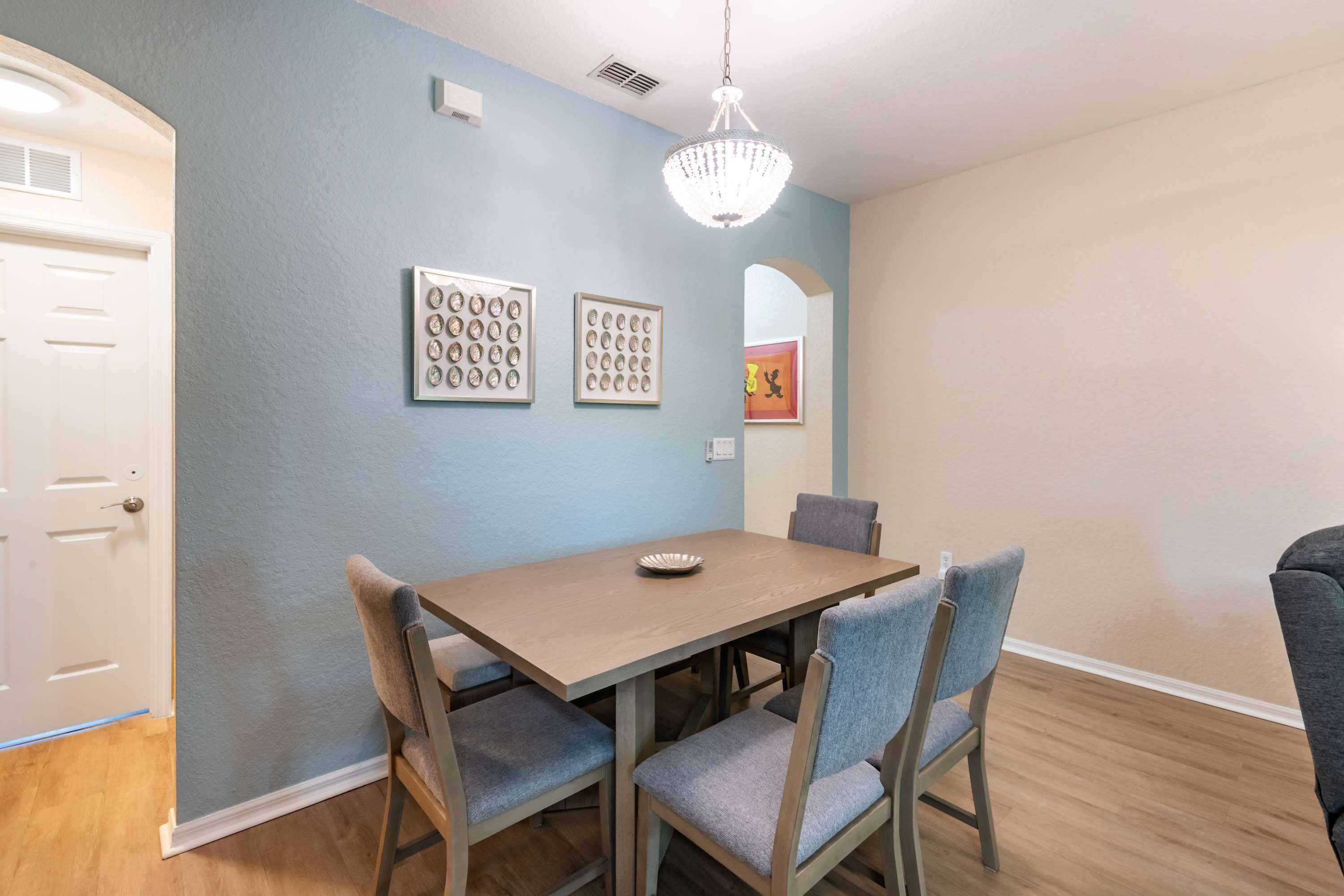 Un espace repas comprenant une table, des chaises et un lustre.