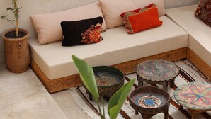A cozy seating area with a sofa, cushions, and a potted plant. - New Luxurious Boutique Riad 4bdr Private house (Marrakech)