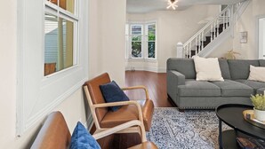 A living room with a sofa, a coffee table, and a chair. There is a staircase leading to another level.