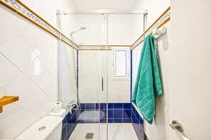 Ein Badezimmer mit Dusche, Toilette, Waschbecken und Handtuchhalter.