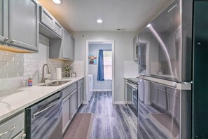 Una cocina moderna con gabinetes grises, electrodomésticos de acero inoxidable y un salpicadero de mármol.