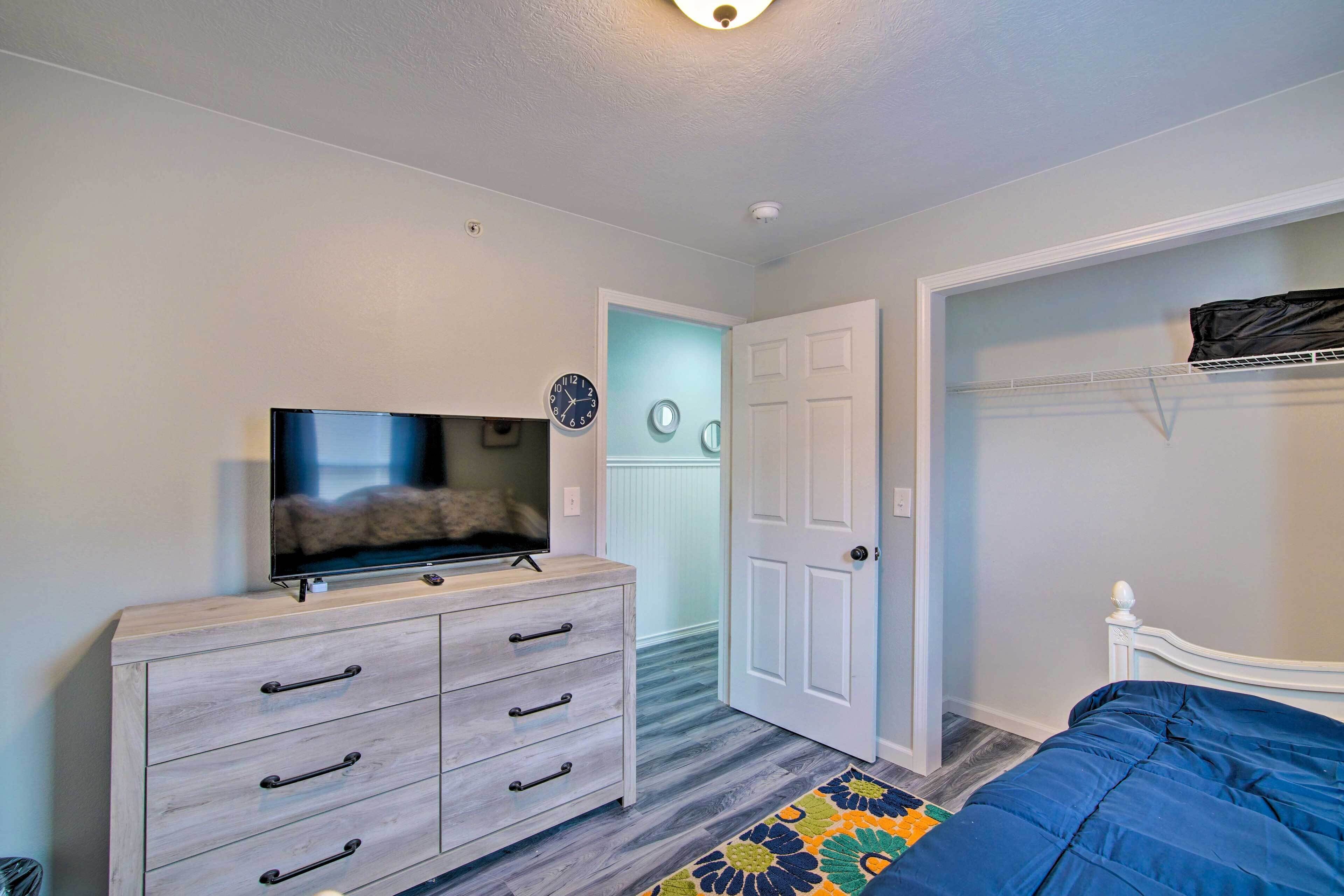 A bedroom with a bed, a dresser, a television, a door, and a closet.