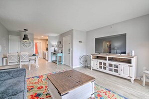 Ein Wohnzimmer mit Fernseher, Couchtisch aus Holz und farbenfrohem Teppich.