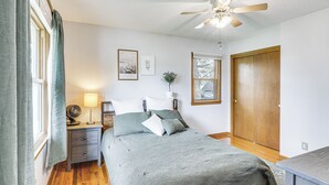 Una camera da letto con un letto, un comodino, una lampada e una ventola a soffitto.
