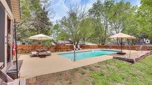 Un giardino con piscina, mobili da patio e ombrelloni.