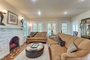 A living room with a fireplace, two sofas, a coffee table, and artwork on the walls.