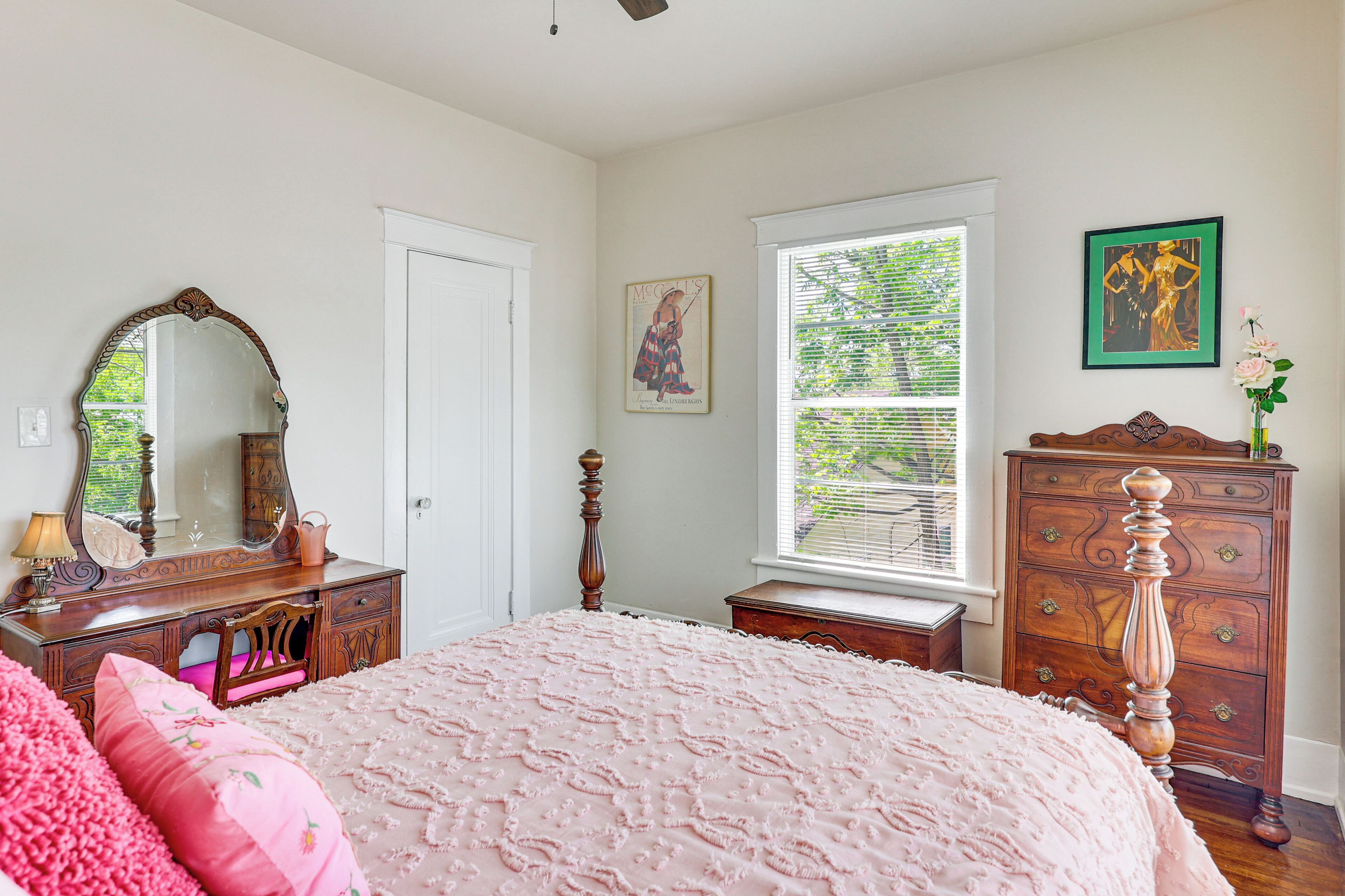 A bedroom with a bed, dresser, mirror, and window.
