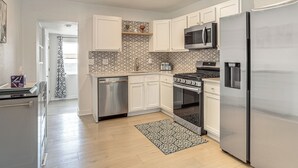 A modern kitchen with white cabinets, stainless steel appliances, and a patterned backsplash. - 2 Mi to Cherry Creek Trail! Family Home w/ Patio (Denver)