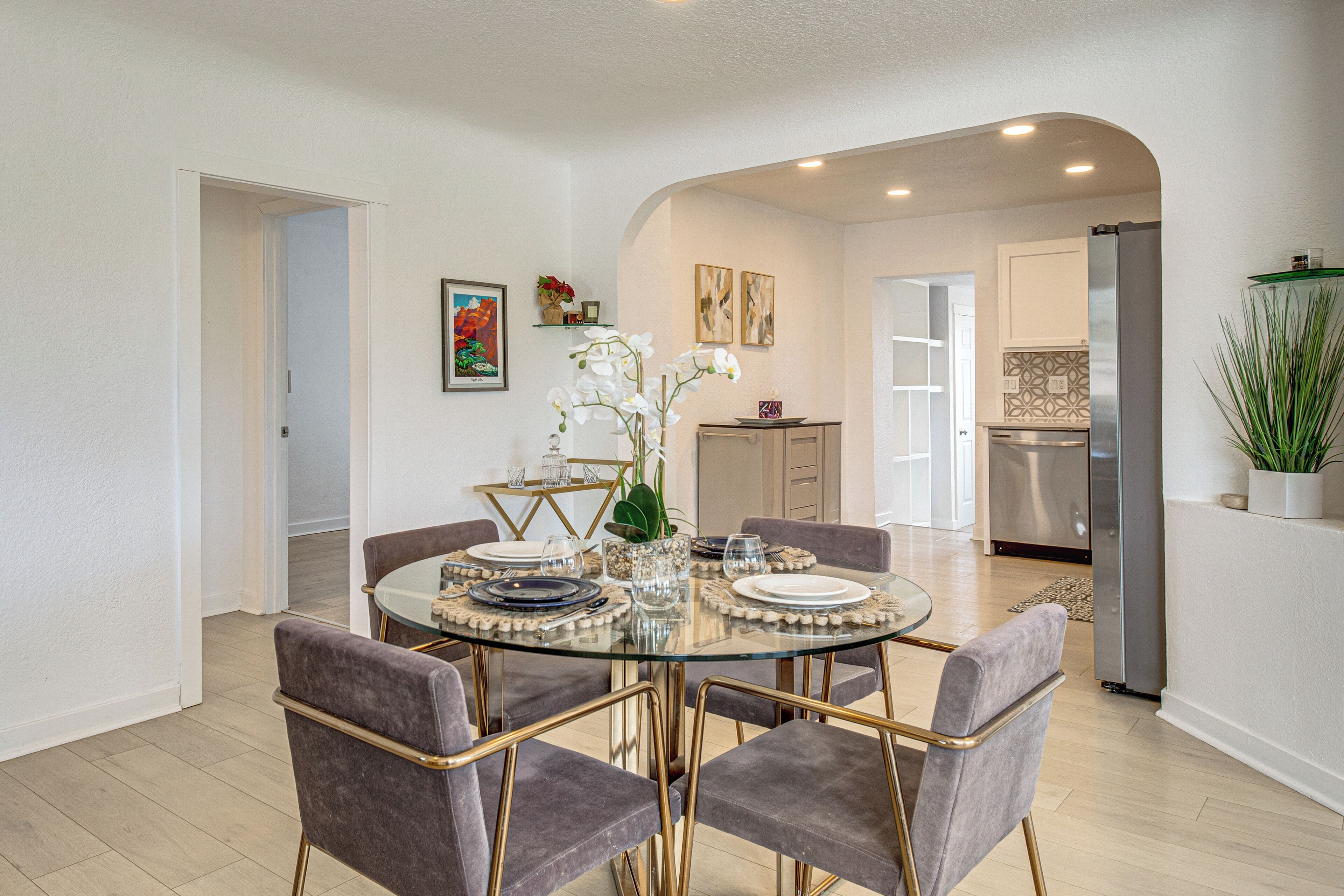 A modern dining area with a glass table, grey upholstered chairs, and a decorative centerpiece.