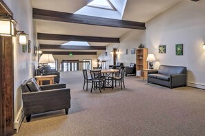 A spacious lobby with a high ceiling, a skylight, a round table with chairs, a sofa, and a bookshelf. - Walk to Trails & Hideaway Park! Main Street Condo (Winter Park)