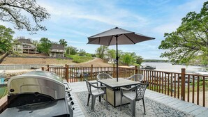 A deck with a grill, table, chairs, and an umbrella. - Dock + Swim Platform! Osage Beach Waterfront Home (Osage Beach)