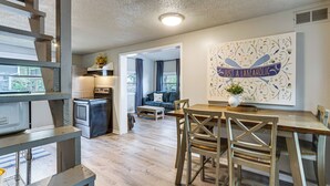 A modern kitchen with a dining area, a living room with a sofa and curtains, and a wall with a decorative sign. - Dock + Swim Platform! Osage Beach Waterfront Home (Osage Beach)