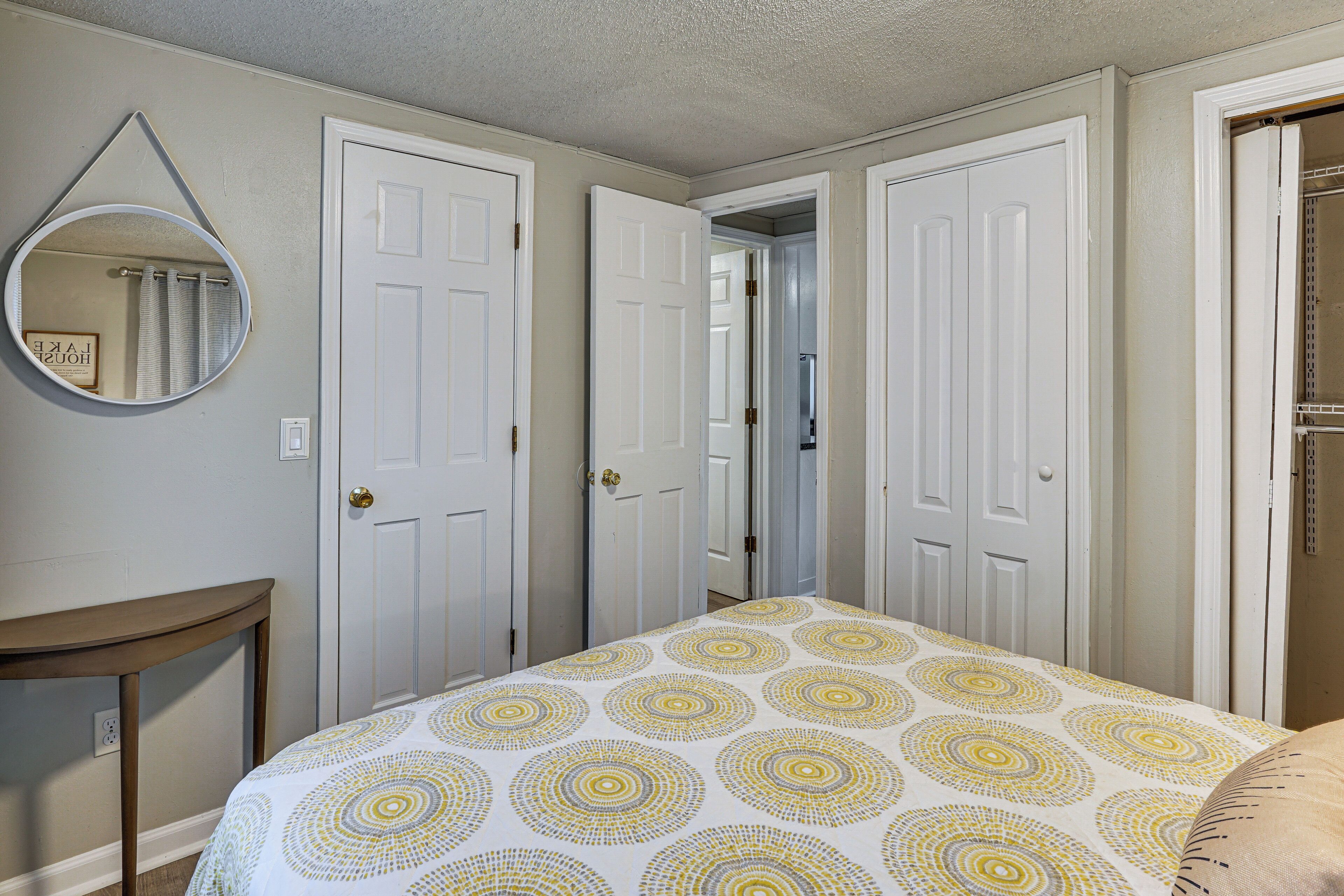A bedroom with a bed, a round mirror, and two white doors.