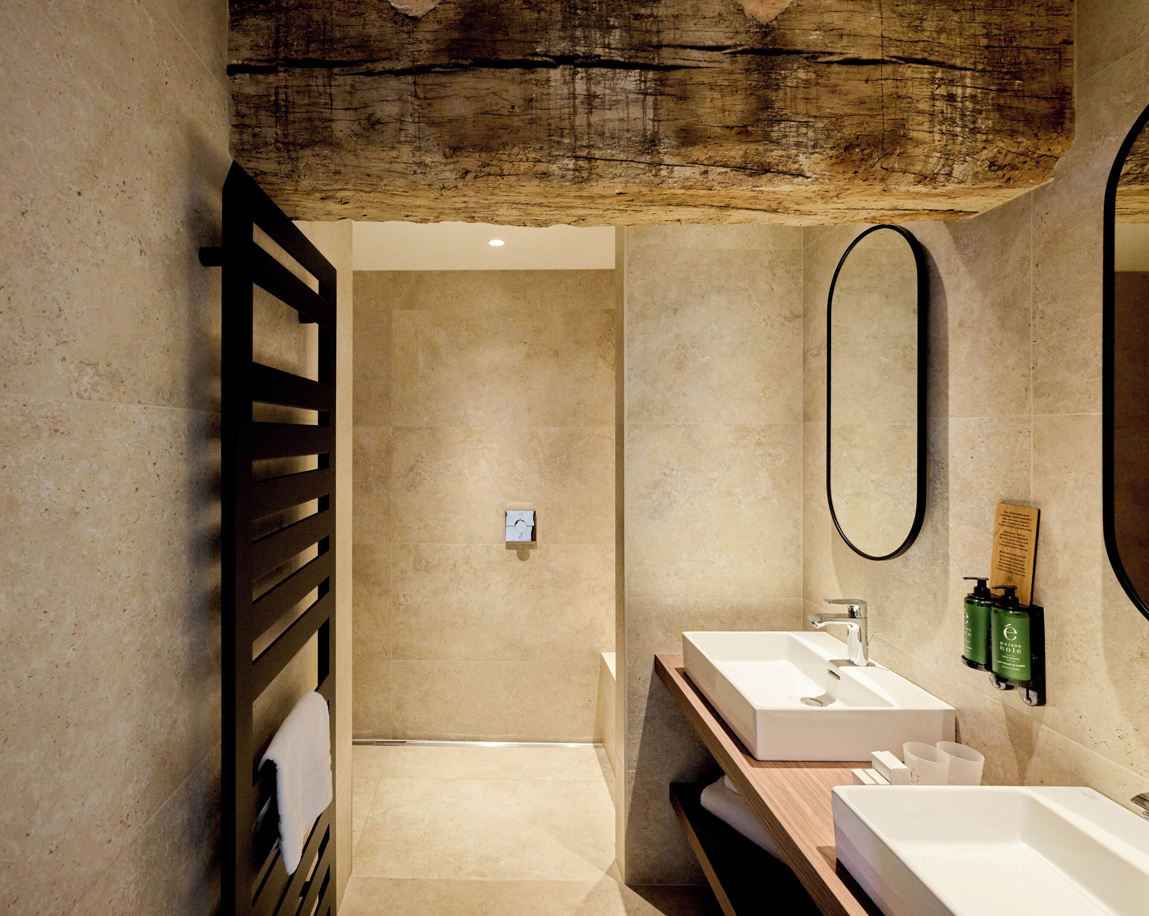 A modern bathroom with two sinks, a large mirror, and a wooden ceiling.