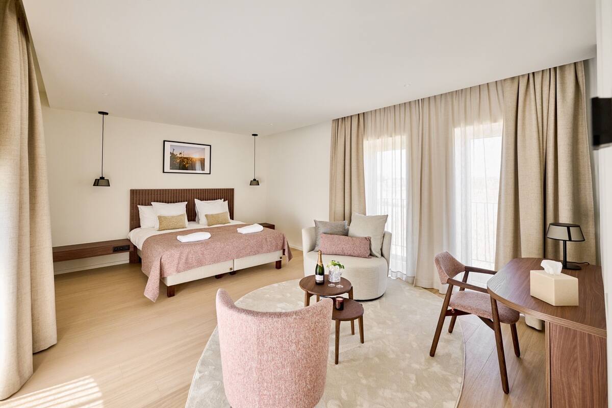 Une chambre d’hôtel avec un grand lit, un canapé, un bureau et une chaise.