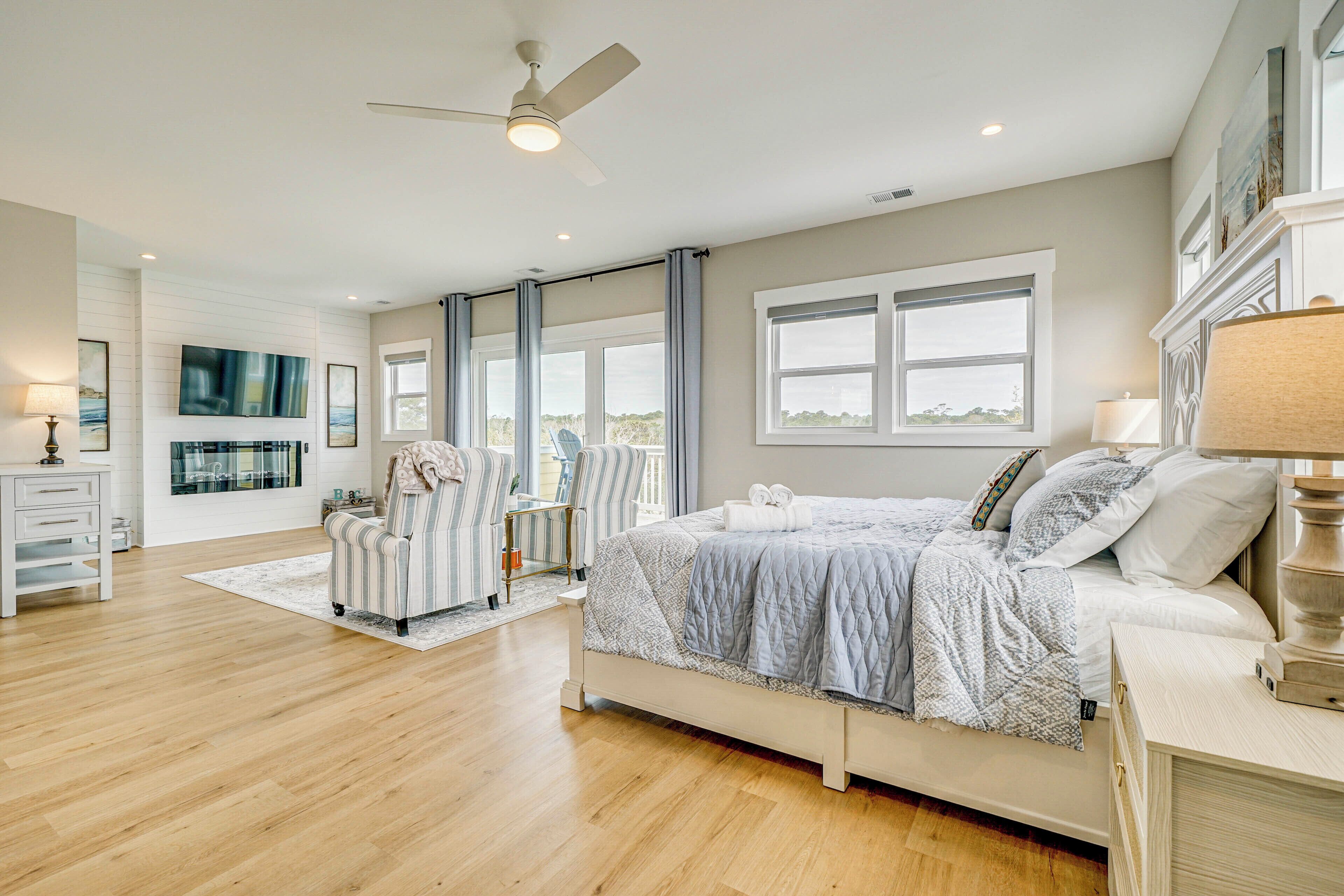 Un dormitorio espacioso con una cama grande, ventilador de techo y vistas al exterior.
