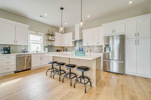 A modern kitchen with white cabinets, stainless steel appliances, and a central island with stools.