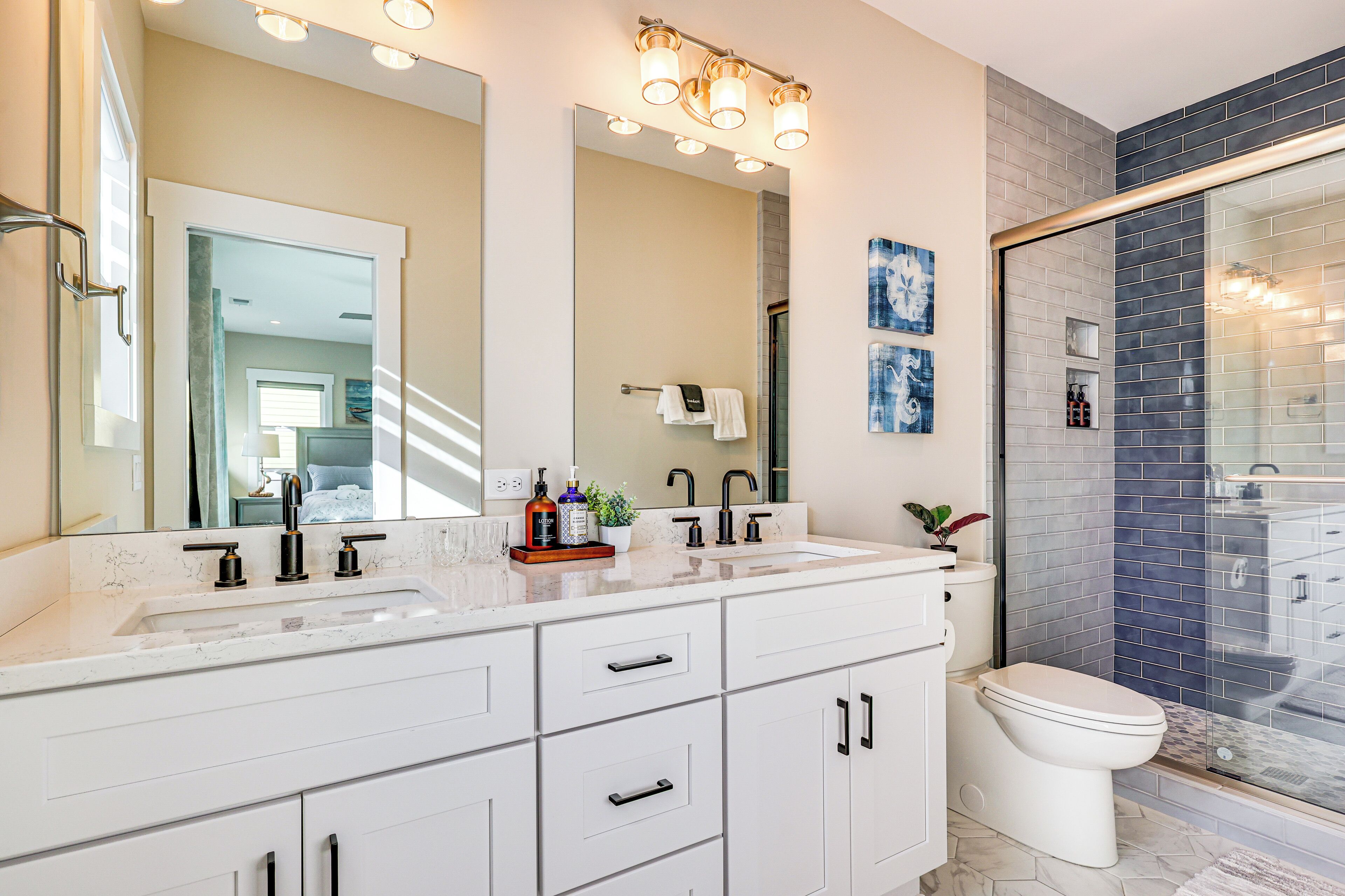 A modern bathroom with a double sink vanity, a large mirror, and a glass-enclosed shower area.