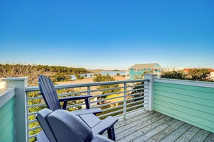 Un pontile in legno con una sedia, vista su una spiaggia e un edificio con tetto blu.