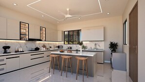 A modern kitchen with a central island, bar stools, and a large window.