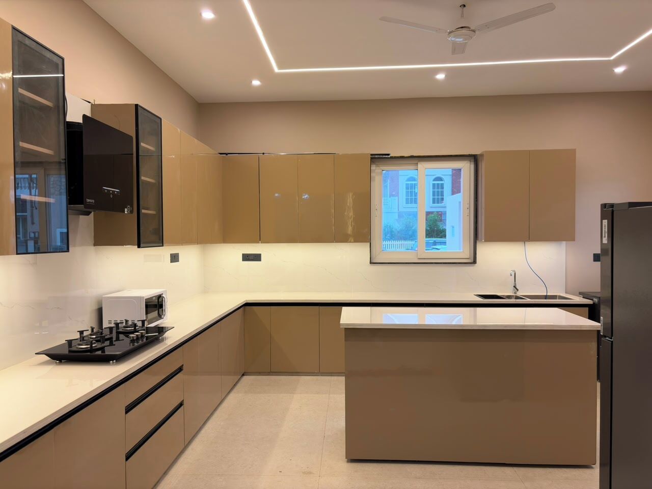 Cocina moderna con una isla central, electrodomésticos integrados y una ventana con vistas.