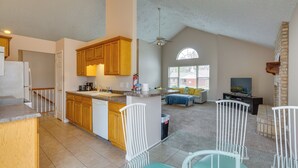 A spacious kitchen with wooden cabinets, a central island, and a dining area with white chairs. - 4 Mi to Ha Ha Tonka State Park! Home w/ Deck (Camdenton)
