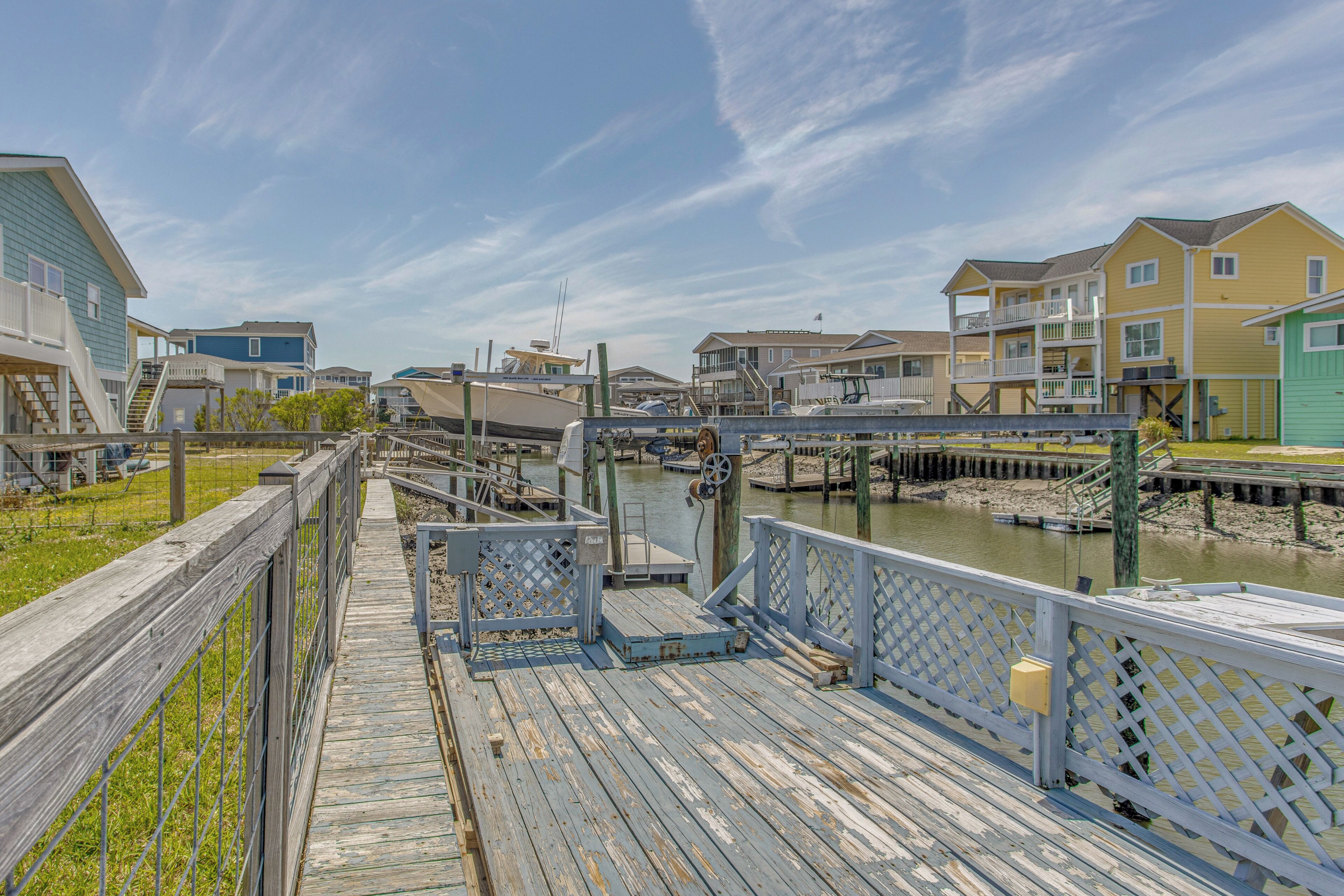 A wooden pier leading to a marina with boats, surrounded by multi-story buildings with balconies.