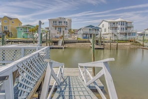 A wooden pier leading to a calm water body with houses in the background. - Steps to Shore! Canal-front Escape in Holden Beach (Supply)