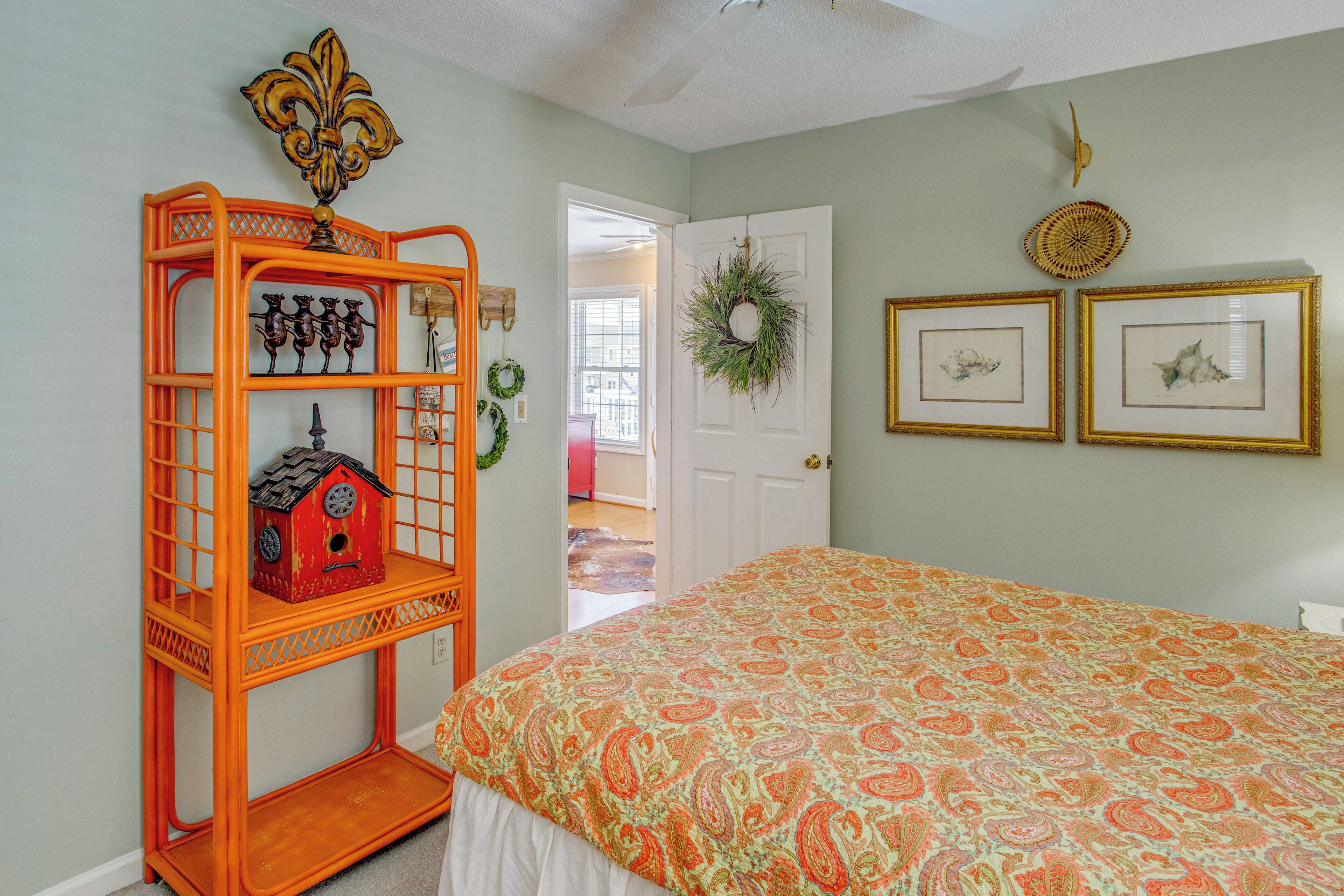 A bedroom with a bed, a dresser, a door, and a wall with two framed pictures.