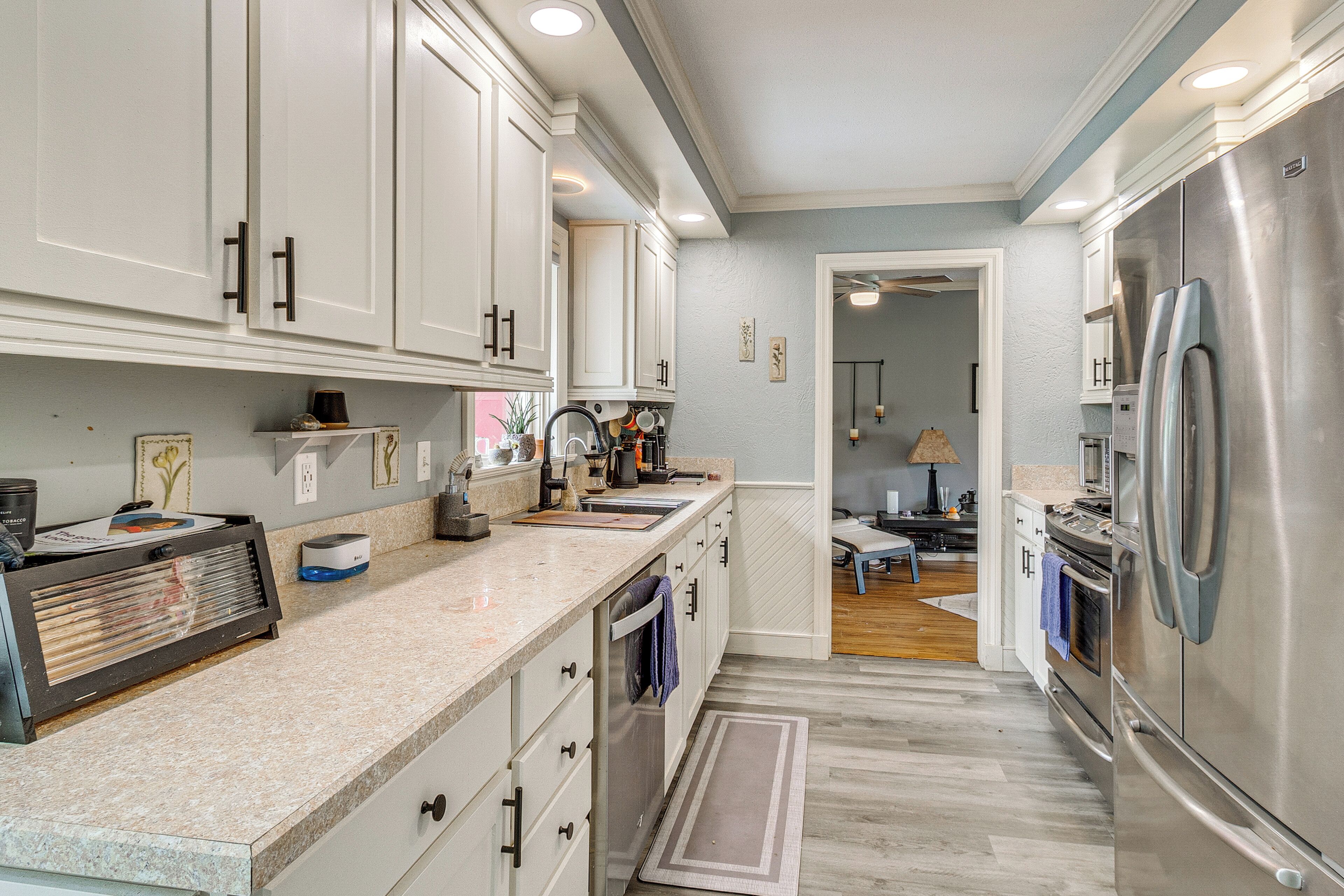 A modern kitchen with white cabinets, stainless steel appliances, and a marble countertop.