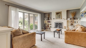 A living room with a fireplace, two sofas, a coffee table, and a bookshelf. - Backyard Oasis w/ Hot Tub & Greenhouse! Toledo Gem (Toledo)