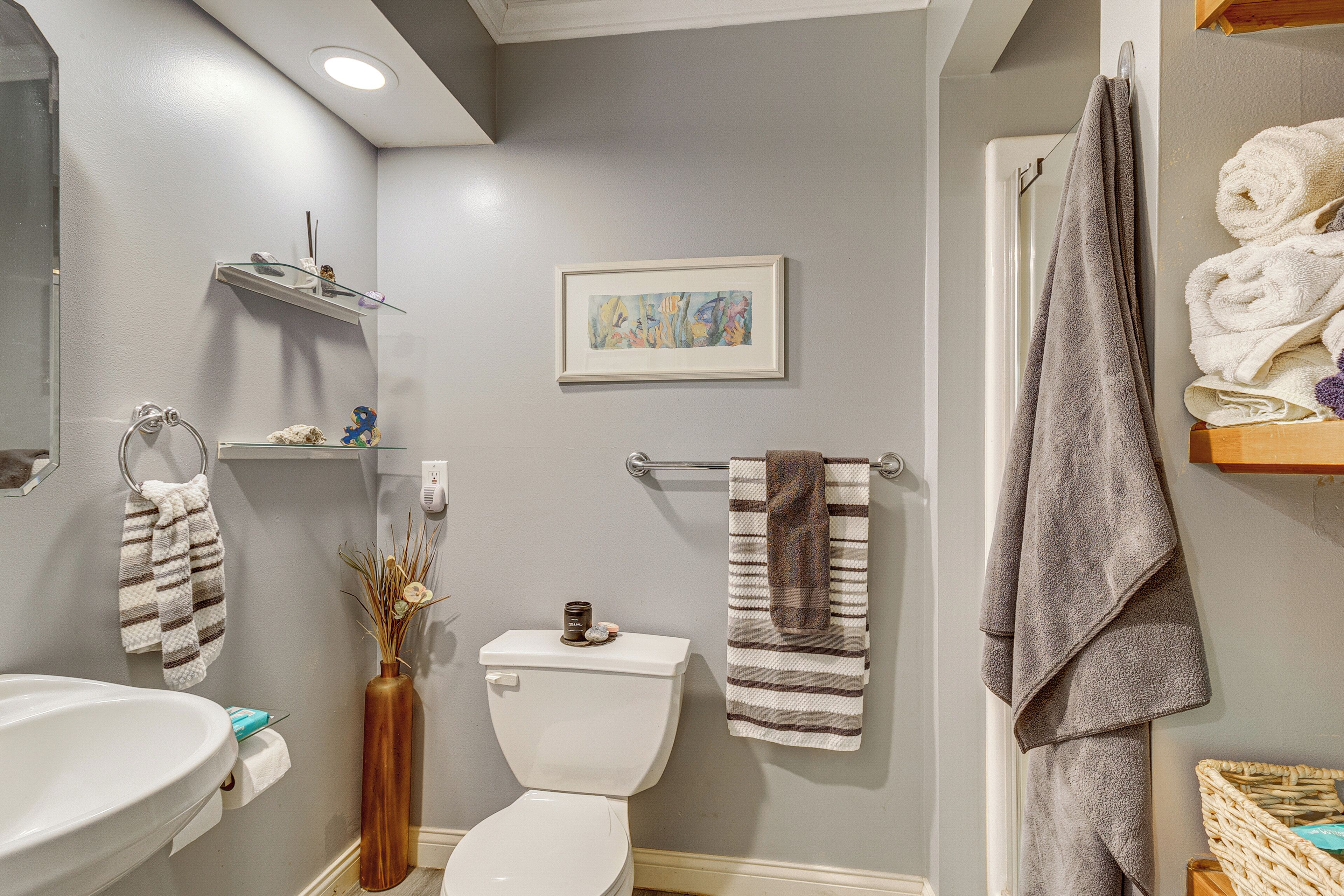 A bathroom with a toilet, sink, towel rack, and a framed picture on the wall.