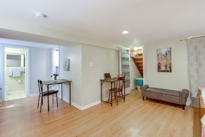 A spacious room with hardwood flooring, a dining table with chairs, a sofa, and a staircase leading to an upper level. - Gateway to Downtown Baltimore! Cozy & Private Unit (Baltimore)