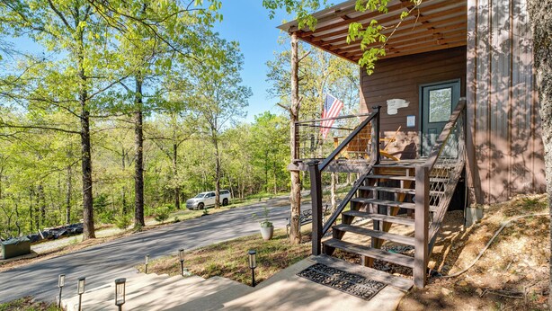 Une cabane avec une façade en bois, une véranda et un escalier menant à une terrasse.