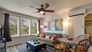 Un salon comprenant un canapé, une table à manger avec des chaises, un ventilateur de plafond et des œuvres d’art accrochées au mur.