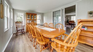 Un coin repas avec une table et des chaises en bois, un fauteuil à bascule et une bibliothèque en bois.