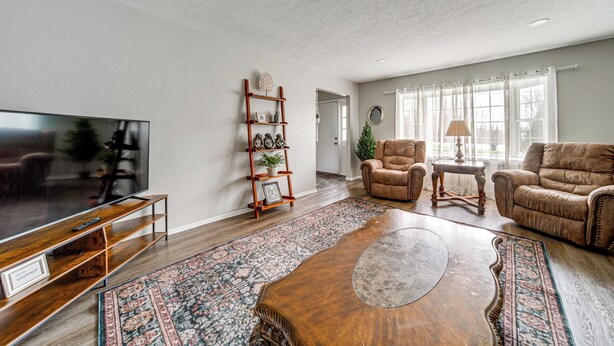 Un salon doté d’un téléviseur à écran plat, de canapés en cuir, d’une table basse, d’une étagère en bois et d’un tapis à motifs.