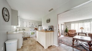 Une cuisine spacieuse avec des meubles blancs, un îlot central et un coin repas comprenant une table et des chaises en bois.
