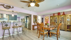 A dining area with a wooden table and chairs, a ceiling fan, and a kitchen in the background. - Dockside Hernando Beach Retreat w/ Canal Access (Spring Hill)