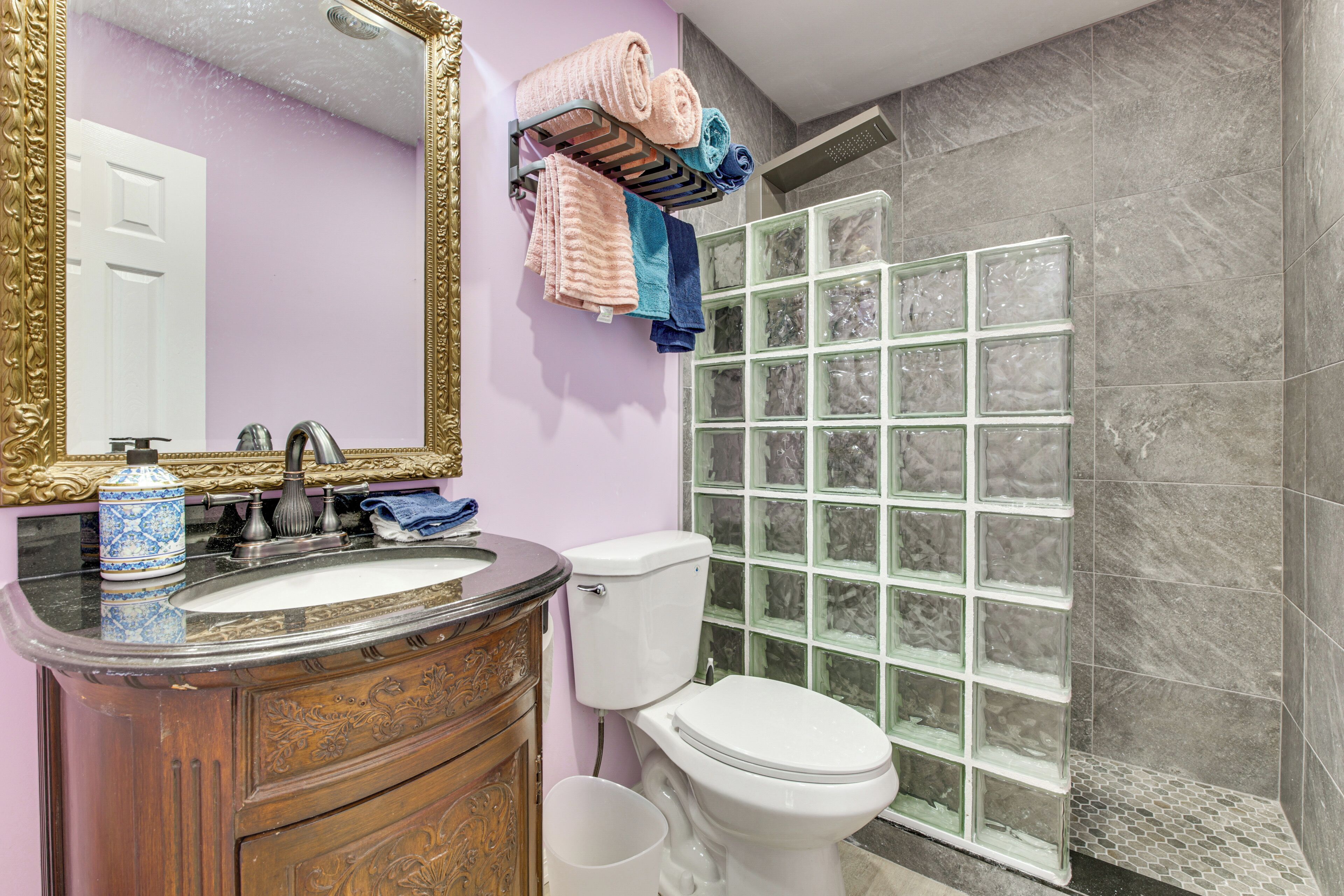 Une salle de bain comprenant un meuble-lavabo, un évier, un miroir, des toilettes et une douche avec une porte en verre.
