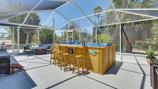 A covered outdoor area with a pool, bar stools, and chairs. - Dockside Hernando Beach Retreat w/ Canal Access (Spring Hill)
