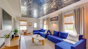 A modern living room with a blue sofa set, a wooden coffee table, and a ceiling with a textured design. - Explore Dtwn Sandusky! Unique Lake Erie Getaway (Sandusky)