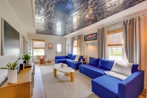 A modern living room with a blue sofa set, a wooden coffee table, and a ceiling with a textured design. - Explore Dtwn Sandusky! Unique Lake Erie Getaway (Sandusky)