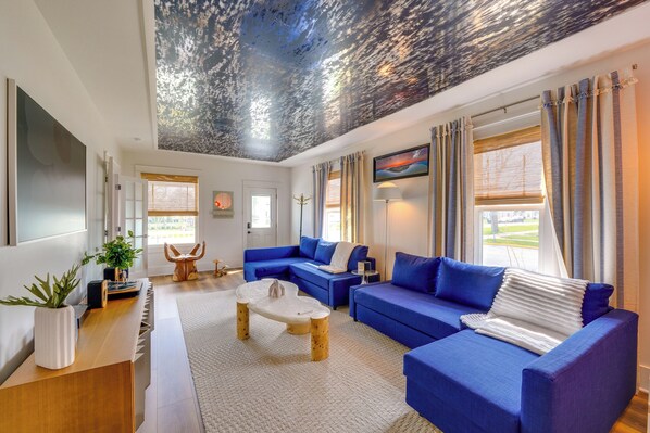 A modern living room with a blue sofa set, a wooden coffee table, and a ceiling with a textured design. - Explore Dtwn Sandusky! Unique Lake Erie Getaway (Sandusky)