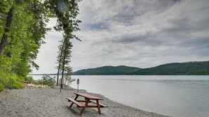 Una mesa de picnic junto a un lago, con vistas a colinas en la distancia.