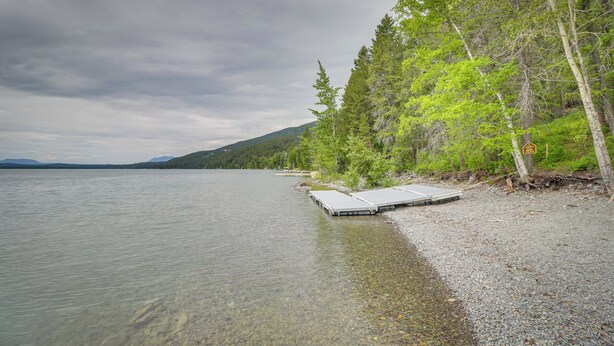 Ein See mit klarem Wasser, einer Anlegestelle und bewaldeter Uferlinie.