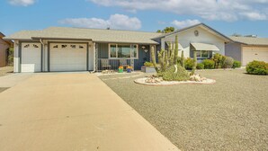 A single-story house with a garage, a covered porch, and a landscaped front yard with a cactus and small shrubs. - On Sun City South Golf Course! Quiet Home w/ Patio (Sun City)
