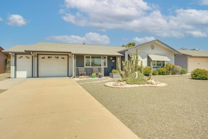 A single-story house with a garage, a covered porch, and a landscaped front yard with a cactus and small shrubs. - On Sun City South Golf Course! Quiet Home w/ Patio (Sun City)
