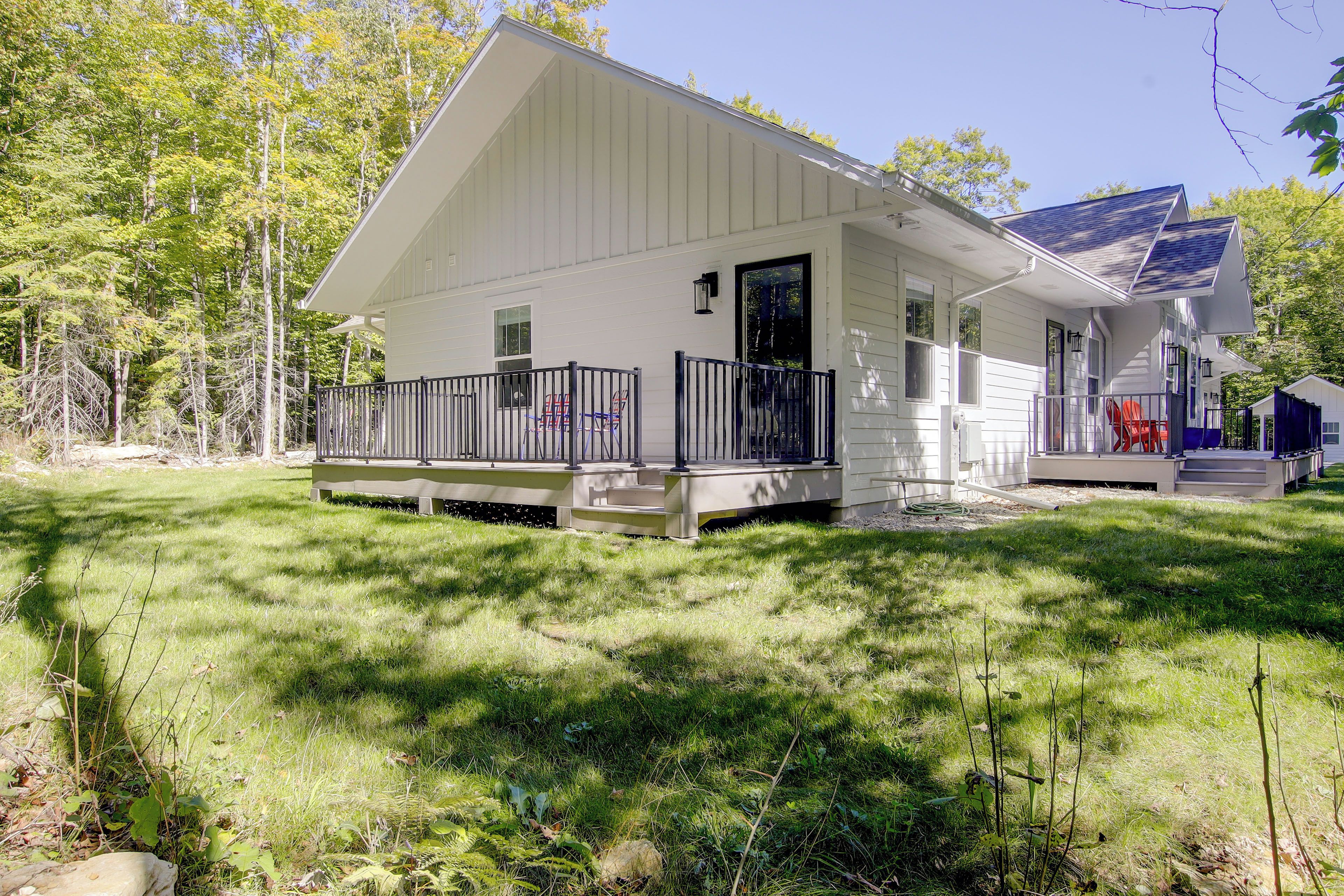 A single-story house with a covered porch, a small deck, and a solar panel array.