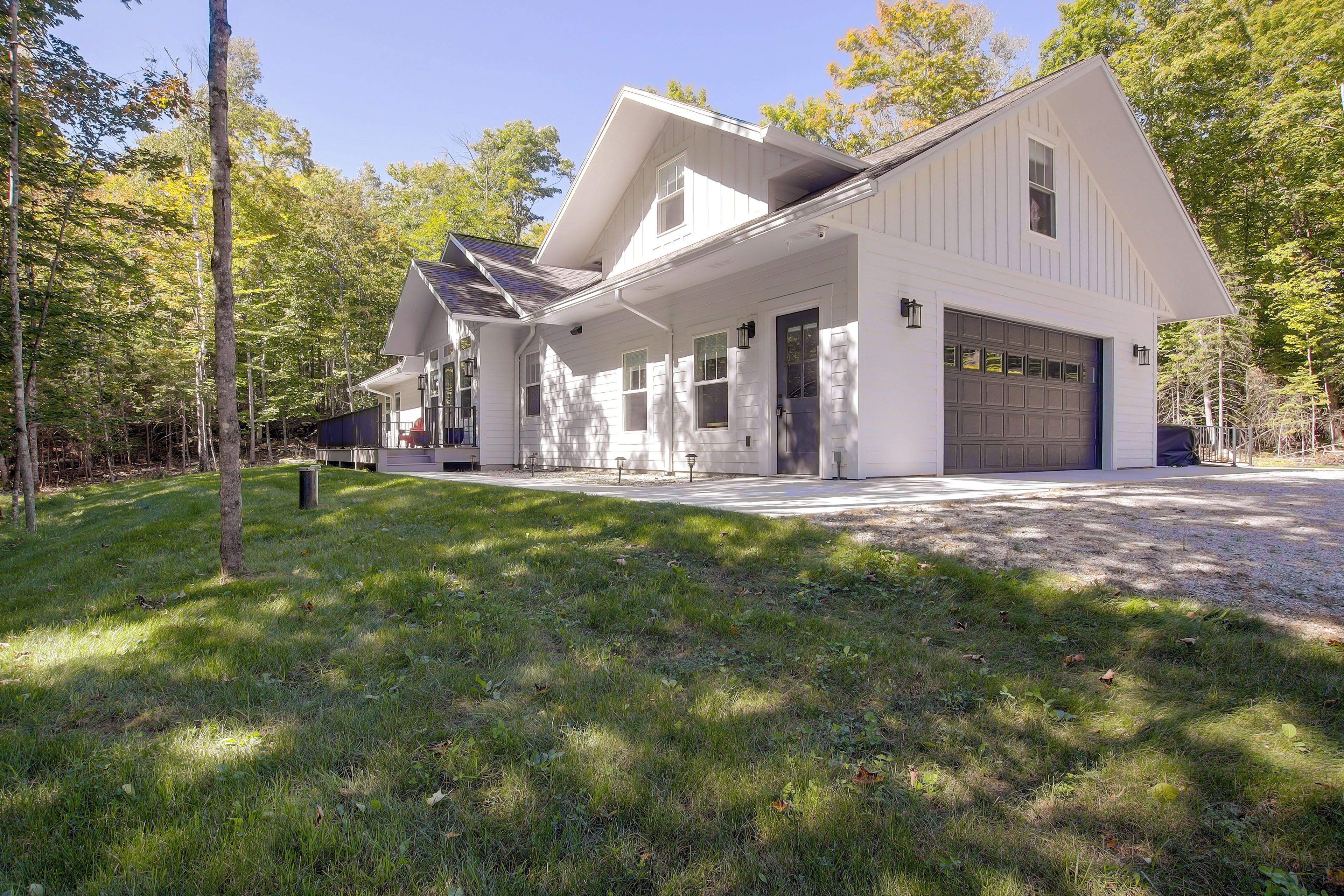 A two-story house with a garage, surrounded by a well-maintained lawn and trees.
